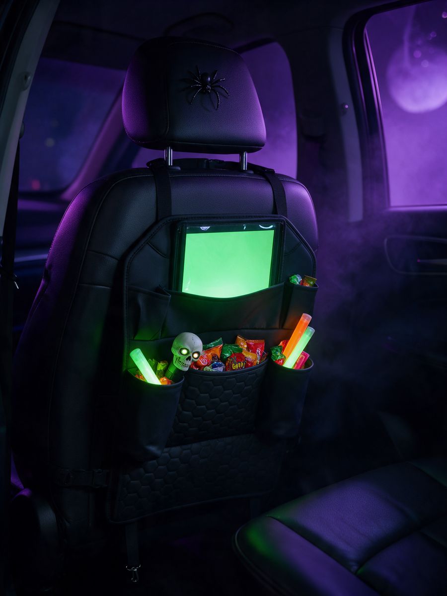 Black Hexy back-of-seat organizer in a dark car with a glowing tablet and candy